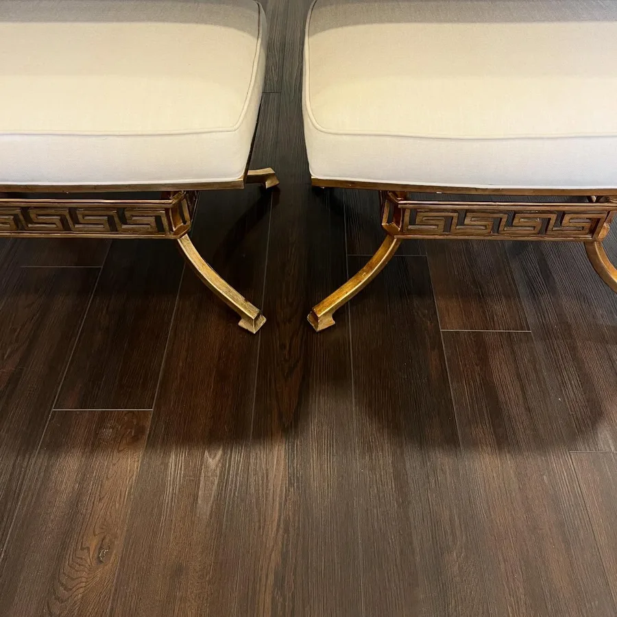 Cream upholstered benches with gilded legs on the dark wood floor