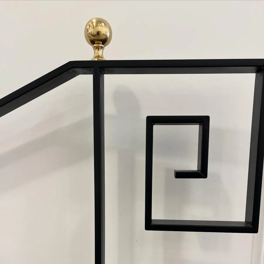 The black Greek-key stair railing with a brass ball finial